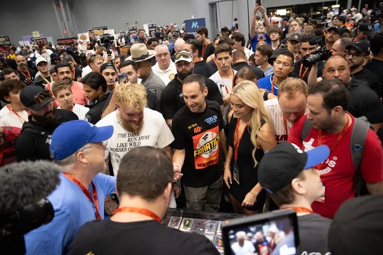 Jake Paul (left), Michael Rubin, and Livvy Dunne look at trading cards during Fanatics Fest at the Javits Center in New York.