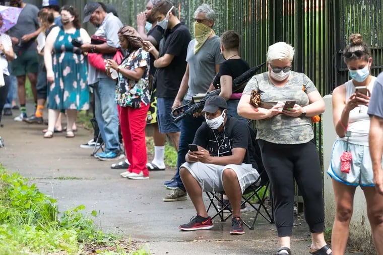 Steven Posey checks his phone as he waits in line to vote at Central Park in Atlanta. Voters reported wait times of three hours.