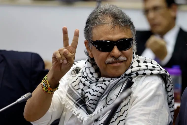 FILE - In this June 12, 2019 file photo, former FARC rebel Jesus Santrich gives a victory signal to journalists as he attends a session of the Chamber of Representatives at the Colombian congress in Bogota, Colombia. United Nations workers assisting in Colombia’s peace process said Monday, July 1, that Santrich, who's real name is Seuxis Hernandez has gone missing, raising concerns for his safety. (AP Photo/Fernando Vergara, File)