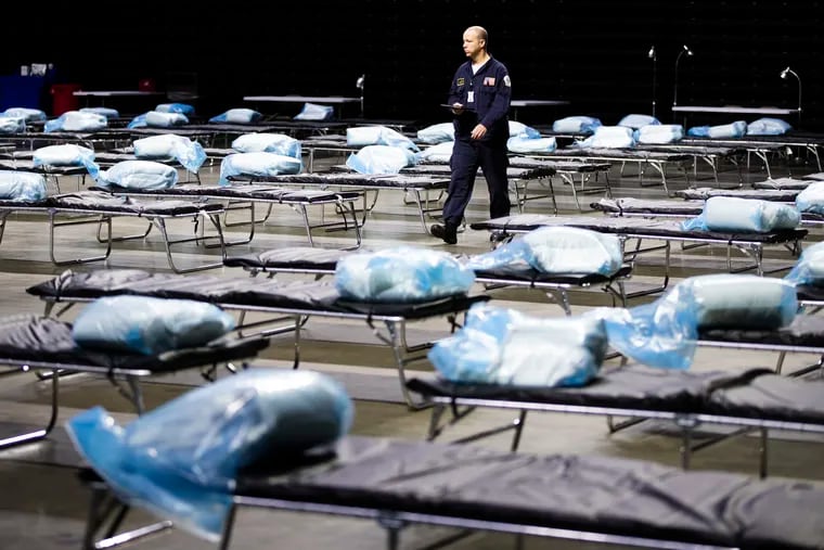 Pennsylvania Task Force 1 member Greg Rogalski walked among the beds of a Federal Medical Station for hospital surge capacity set up at Temple University's Liacouras Center in Philadelphia, Monday, March 30, 2020. So far the center hasn't been reopened as an overflow facility amid the recent surge. (AP Photo/Matt Rourke)