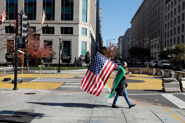 A man walks with an American flag outside the White House in Washington, D.C., on Nov. 6, 2020.