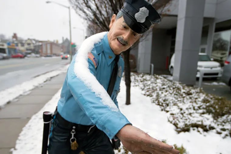 A statue of a policeman on the sidewalk Saturday, Jan. 24, 2015, in Ardmore seems to measure the amount of snow that fell.