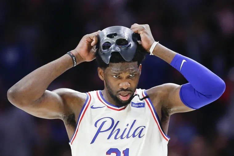 Sixers center Joel Embiid adjust his facial mask against the Miami Heat in game five of the Eastern Conference quarterfinals on Tuesday, April 24, 2018 in Philadelphia. YONG KIM / Staff Photographer