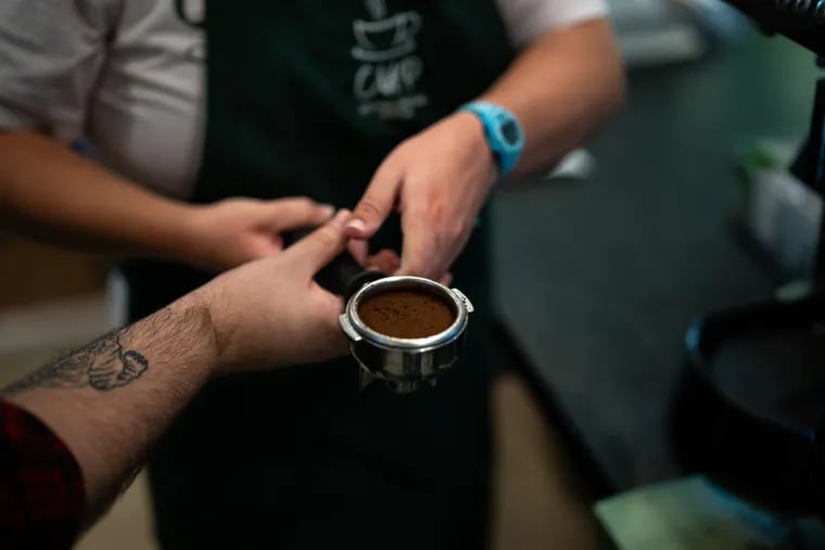 Barista Maggie Mahon and assistant manager Joe Mansion work together to prepare an espresso shot. MUST CREDIT: Thomas Simonetti for The Washington Post