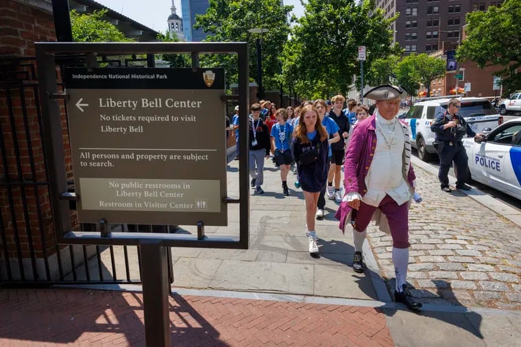 A colonial period tour guide walks with students along South Sixth Street near the Liberty Bell and Independence Hall.