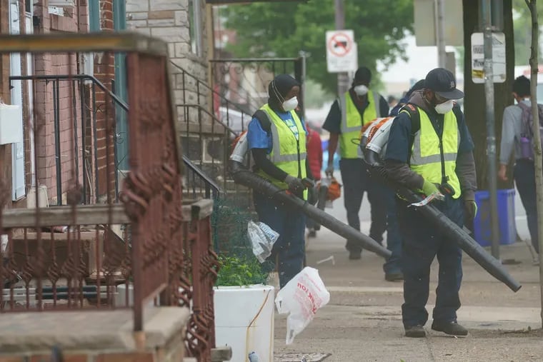 Street Sweeping crews blow trash into the street to be picked up by a truck, on South 7th street, in Philadelphia, May 2, 2019.