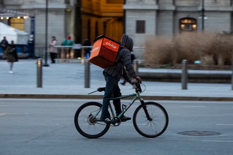 A biker riding for Caviar passing City Hall with a delivery backpack on Jan. 22.