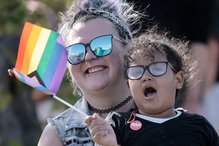 4 year old Nicole Woodson of Voorhees waves a pride flag while sitting with Madison Kirsteins of Somerdale during the 16th Annual 'Out in the Park' Festival at Cooper River Park in Pennsauken.