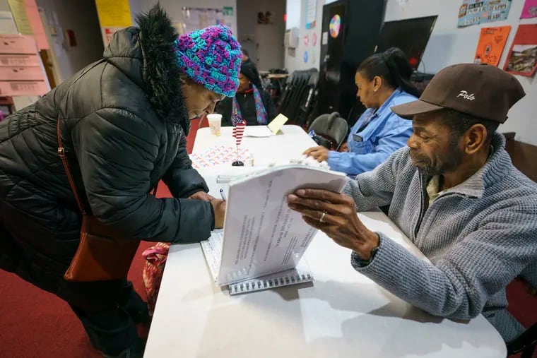 Denise King (left) signs in with Robert Kelly (right), majority inspector, at a polling place at Antioch Universal Church on North 52nd Street in Philadelphia on Tuesday.