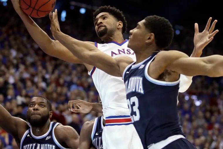 Kansas forward Dedric Lawson, center, rebounds against Villanova forward Jermaine Samuels, right, during the first half of an NCAA college basketball game in Lawrence, Kan., Saturday, Dec. 15, 2018. (AP Photo/Orlin Wagner)