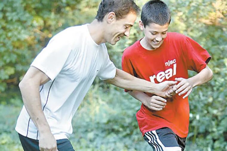 Jarrod Skole, a high school freshman, and his father, Gary, play soccer in their backyard. The two wrote “Imagine What’s Possible,” a child’s-eye view of visualization - the technique of using imagery to lessen anxiety and even pain. (AKIRA SUWA / Staff Photographer)