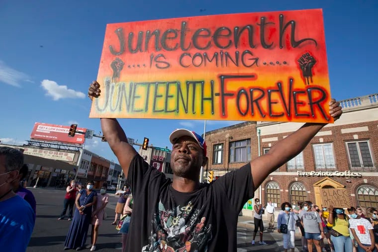 Rich Blye holds up a sign reminding those that Juneteenth, which commenorates the end of slavery in the United Sates is approaching, at the Upper Darby Community Day of Healing on June 10, 2020.