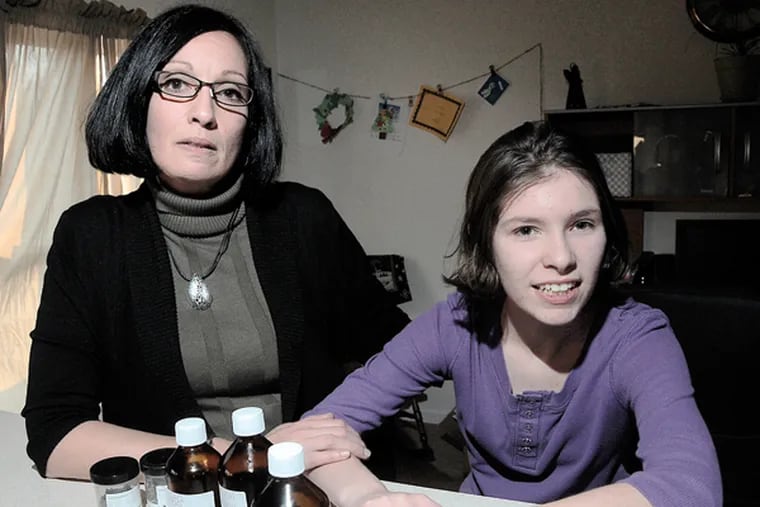 Tina DeSilvio, who a year ago was one of the first moms to concoct a marijuana syrup for her 15-year-old daughter Jenna, right. In front are raw and finished materials, along with a syringe for exact dosage measurements. (FILE: Curt Hudson/Staff)
