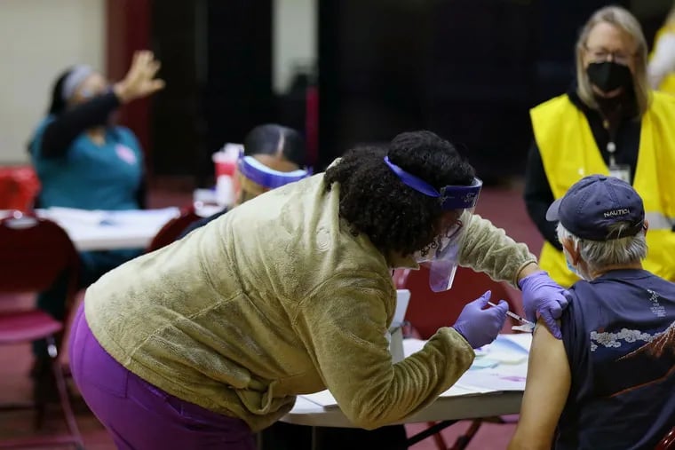 A health care worker vaccinates a man at a community COVID-19 vaccination clinic run by the Philadelphia Department of Public Health in West Philadelphia in February.