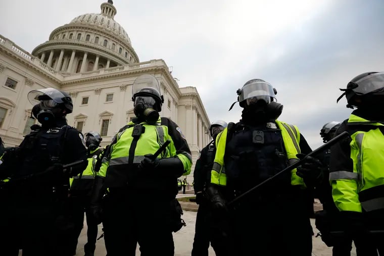 Police officers in riot gear stand guard while supporters of President Donald Trump protest on the steps of the U.S. Capitol Building on Capitol Hill in Washington, D.C., on Wednesday, Jan. 6, 2021.