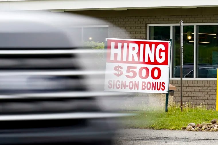 A vehicle speeds by a hiring sign offering a $500 bonus outside a McDonalds restaurant in Cranberry Township, Butler County. Pennsylvania will resume work- search requirements in July for hundreds of thousands of people receiving unemployment compensation.