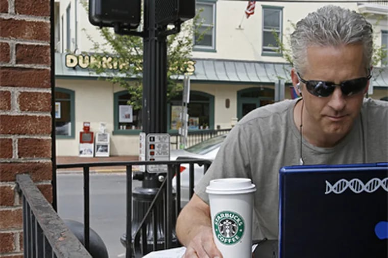 Jon Berndt drinks Starbucks coffee while working on his computer at a corner Starbucks that is across the street from a new Dunkin Donuts. (Michael S. Wirtz / Staff Photographer)