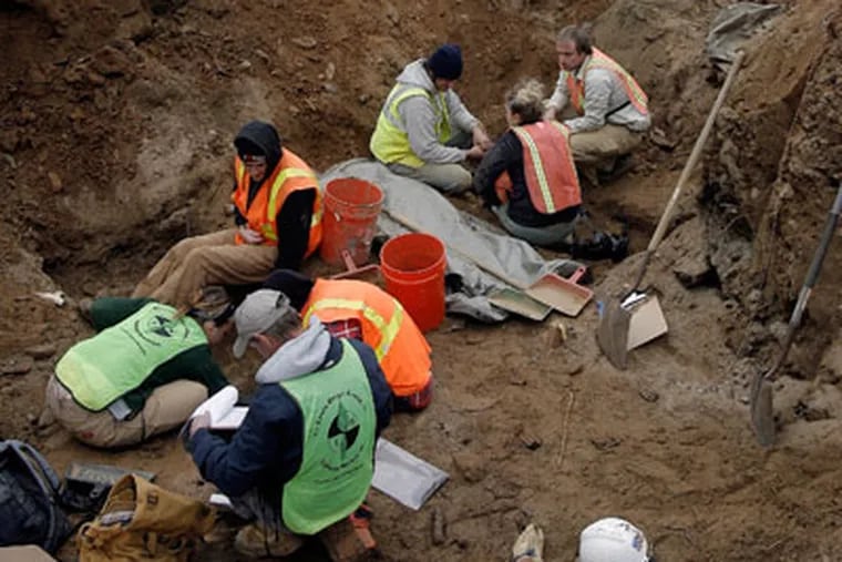 Archaeologists from Louis Berger Group dig at a grave site. (Akira Suwa / Staff Photographer )