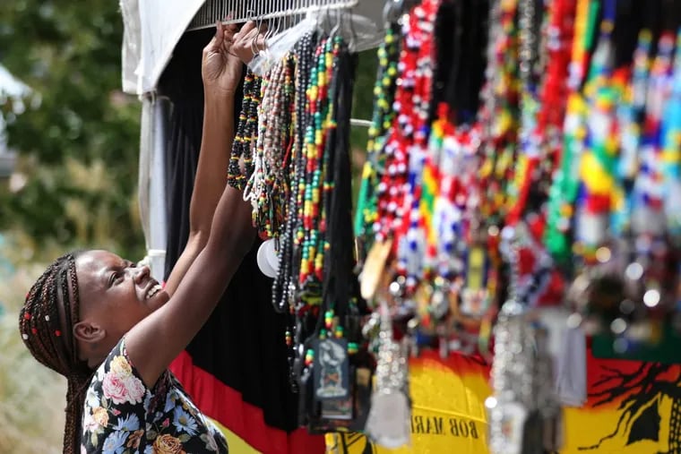 Ashley Tenor hangs up Caribbean-inspired necklaces at her retail booth at the Philadelphia Caribbean Festival. The festival returns this weekend.