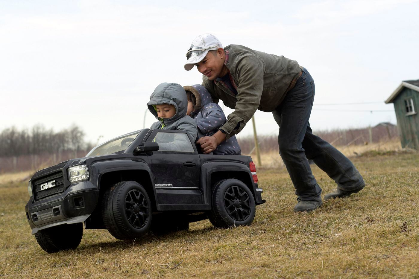 Eladio Beltran pushes his children, Caleb, 4, (left) and Jayem, 3, in their toy car at their home in Albion, N.Y., in 2019. Beltran faces deportation because he was arrested for driving without a license. File Photograph