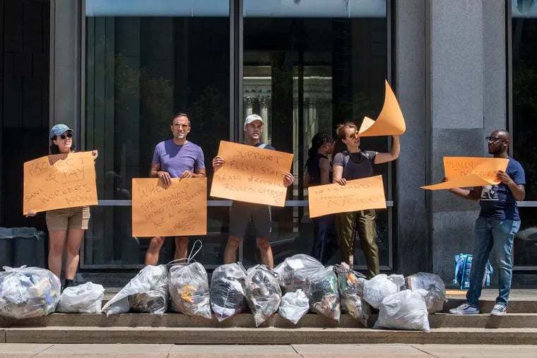 People protest with uncollected trash bags at the Municipal Services Building in Philadelphia, Pa. Wednesday, July 28, 2021.