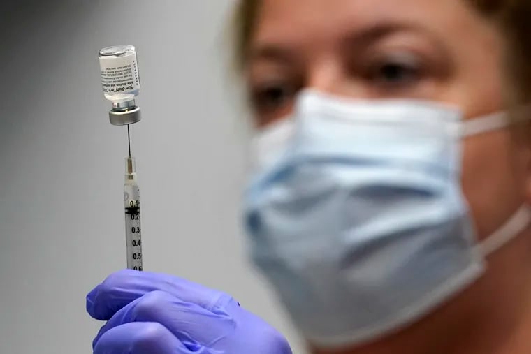 In this March 2 photo, pharmacy technician Hollie Maloney loaded a syringe with Pfizer's COVID-19 vaccine at the Portland Expo in Portland, Maine.