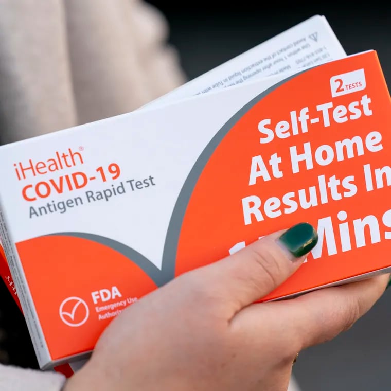 A woman holds two boxes of at-home COVID-19 test kits in Washington on Dec. 22, 2021.