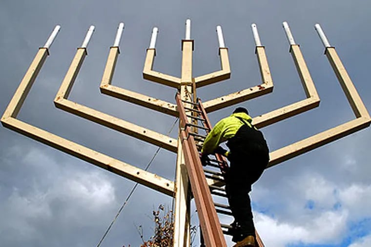 Brian Yohnnson of Moorestown unties the crane after he and co-workers from Mayberry Riggers installed the 37-foot-high menorah Thursday on Independence Mall, where it will be lit Friday evening to mark the first night of Hanukkah. (Tom Gralish / Staff Photographer)