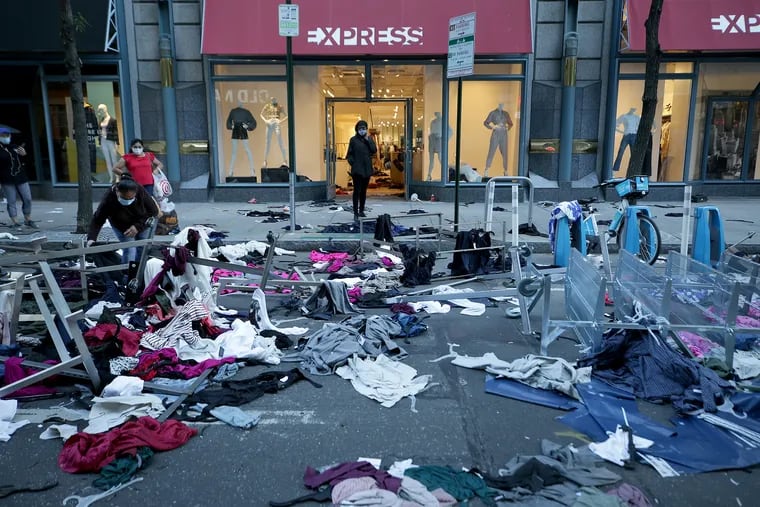 An unidentified woman picks through clothing in the middle of Chestnut Street as clean up begins the day after protests in Philadelphia, Pa. on May 31, 2020. Peaceful protests over the police killing of George Floyd in Minneapolis last week gave way to violence, looting, and vandalism Saturday across the country.