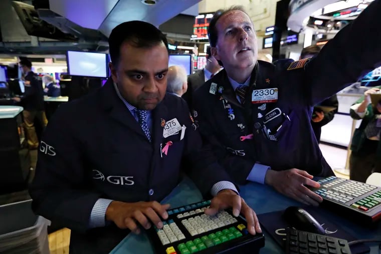 Specialists Dilip Patel, left, and Glenn Carell work at a post on the floor of the New York Stock Exchange.