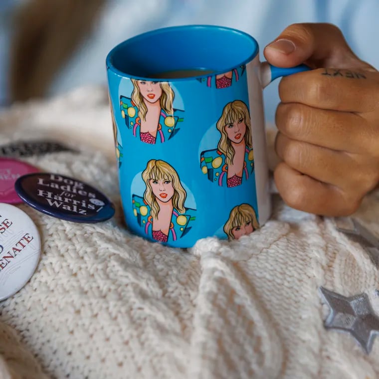 Annie Wu Henry, campaign manager for Swifties for Kamala, holding a coffee cup with images of Taylor Swift on it at her home in Fishtown.