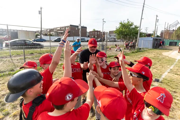 Justin Troccoli, 41, of South Philadelphia, coach for the Angels, gathers his team for a huddle and chant before their game against the Blue Jays at the Southeast Youth Athletic Association in Philadelphia.