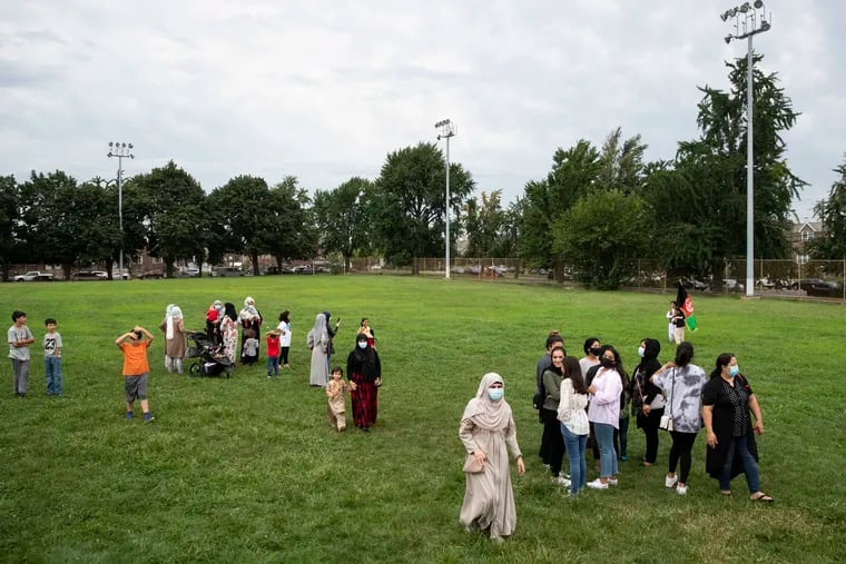 Women and children walk in the grass after a rally in solidarity with the people of Afghanistan and the Afghan community in Philly at Tarken Recreation Center in Northeast Philadelphia on Sunday, Aug. 22, 2021.