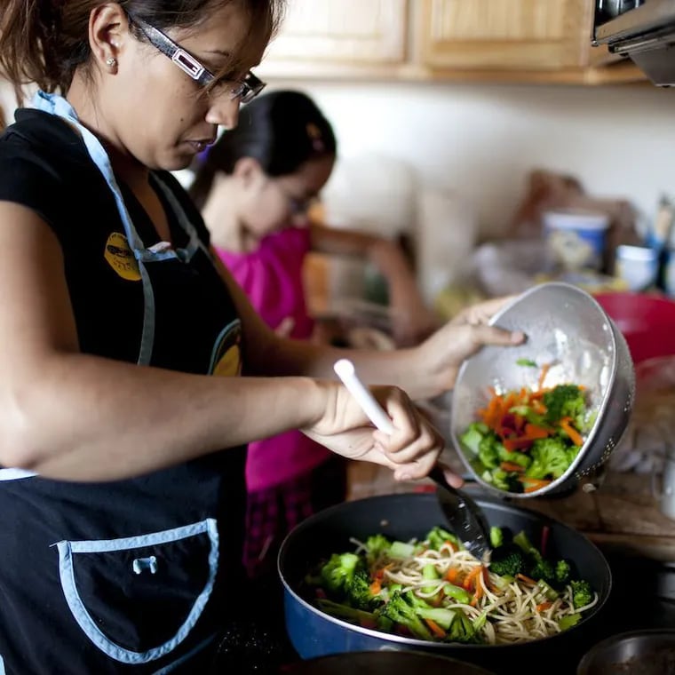 A mother cooks dinner in her kitchen. The Summer EBT program provides families with $120 per child during summer months to increase household grocery budgets.