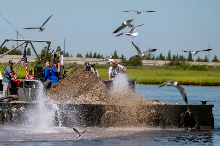 High-pressure water cannons blast oyster shells off a barge into the waters of the Mullica River, where they help bolster the oyster population on reefs below.