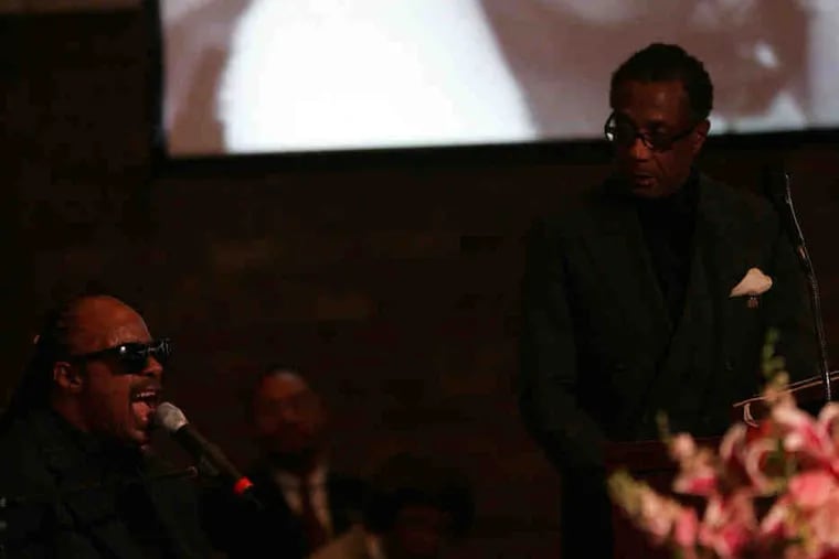 Stevie Wonder sings at the funeral service for Esther Gordy Edwards as her only son, Robert Bullock, looks on.