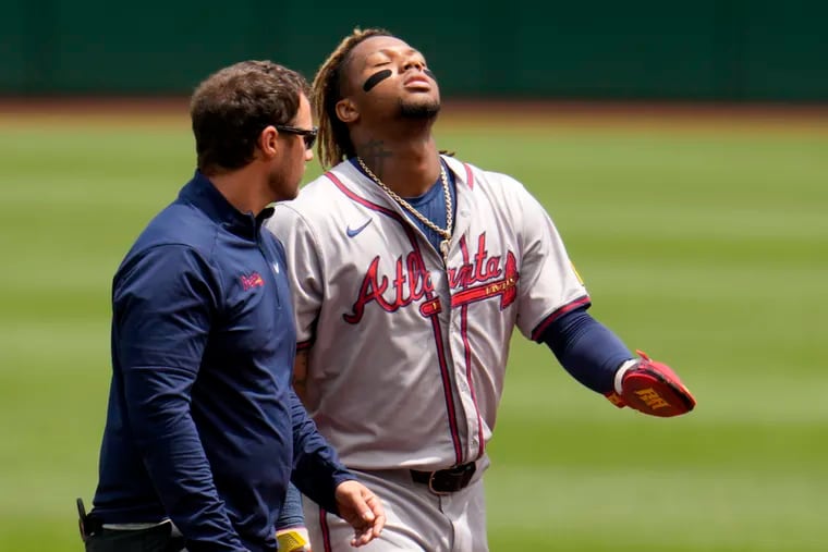 The Braves' Ronald Acuña Jr. walks off the field with a trainer after being injured while running the bases against the Pittsburgh Pirates.