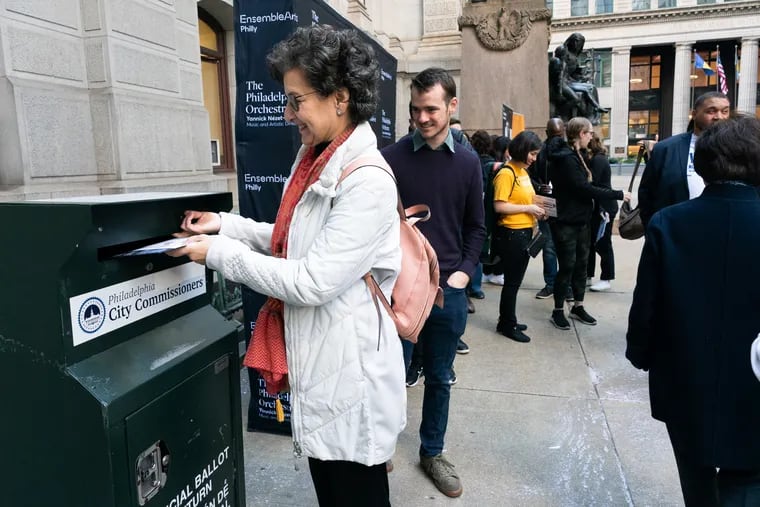 Musician Barbara Govatos, front left, violin, with the Philadelphia Orchestra, puts her ballot in the ballot box in front of City Hall in Philadelphia, as Tobias Vigneau, back center, Assistant Principal Bass, waits to submit his ballot, as musicians and Staff of The Philadelphia Orchestra deliver Absentee Ballots to City Hall before Departing on a tour of China, Tuesday, October 15, 2024.