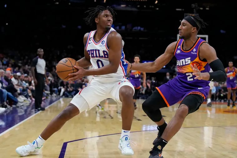 Philadelphia 76ers guard Tyrese Maxey (0) shields the ball from Phoenix Suns forward Josh Okogie on Saturday in Phoenix.