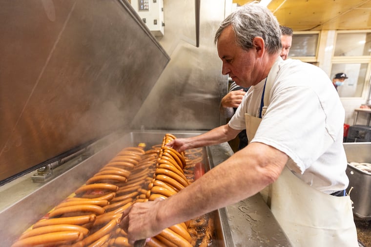 Sausage-maker Alex Naumenko places smoked German wieners into hot water to cook at Rieker’s Prime Meats in Fox Chase.