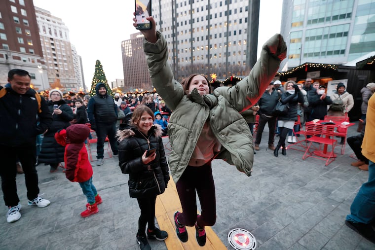 Livia Holtsberg, 8, leaps in the air when her father, Michael Holtsberg of Broomall, Pa., is declared the winner of the bratwurst eating competition during German American weekend at Love Park’s Christmas Village in 2022. Holtsberg ate three bratwurst and nearly three rolls for the win.