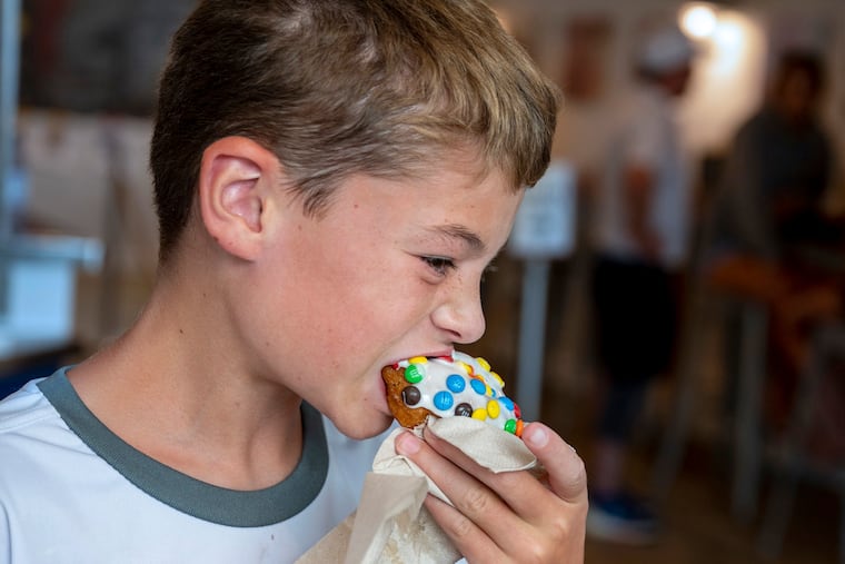 Eleven year-old Logan has a "Stowaway" donut (vanilla icing, M&Ms) at Nauti Donuts in Ocean City, Monday, July 24, 2023. He was there with his parents, Shelly and Mike Pierson and younger brother, Miles, all from East Norriton.