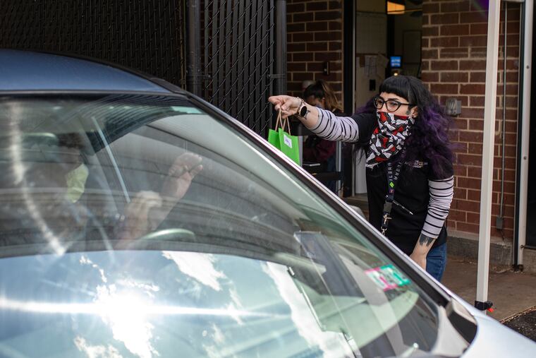 Alexis Poper, 29, of Reading, Pa., Wellness Associate at Apothecarium Dispensary, right, hands Sheila Helge, 61, of Ambler, Pa., left, her online order at the drive through at The Apothecarium Dispensary on Wednesday, April 8, 2020. “I’m glad that they now have a drive through and I don’t have to go inside,” Helge said.