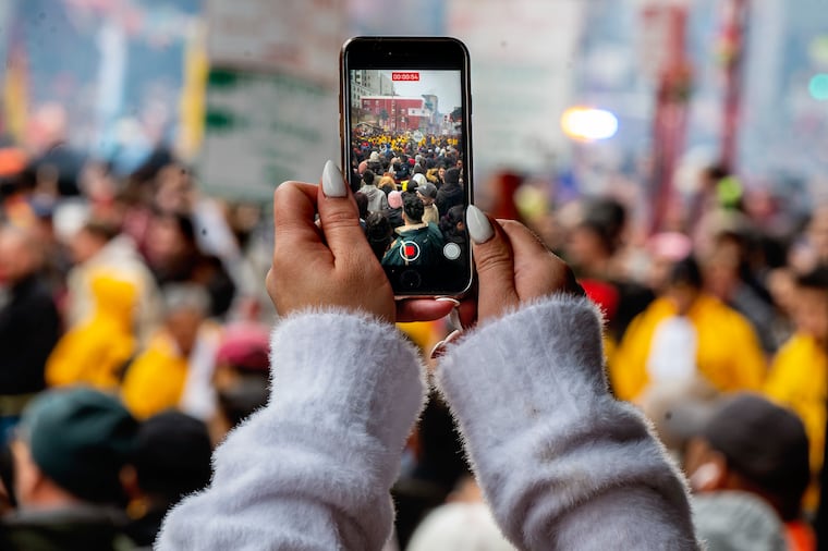 Spectators photograph as the Year of the Dragon kicks off in Chinatown Sunday, Feb. 11, 2024 with the annual Lunar New Year’s Day Parade. The Philly Suns lion dance group lead the way through with dancing, drumming, music, and firecrackers, as part of a cultural celebration to bring good fortune and good luck to the local businesses in the community.