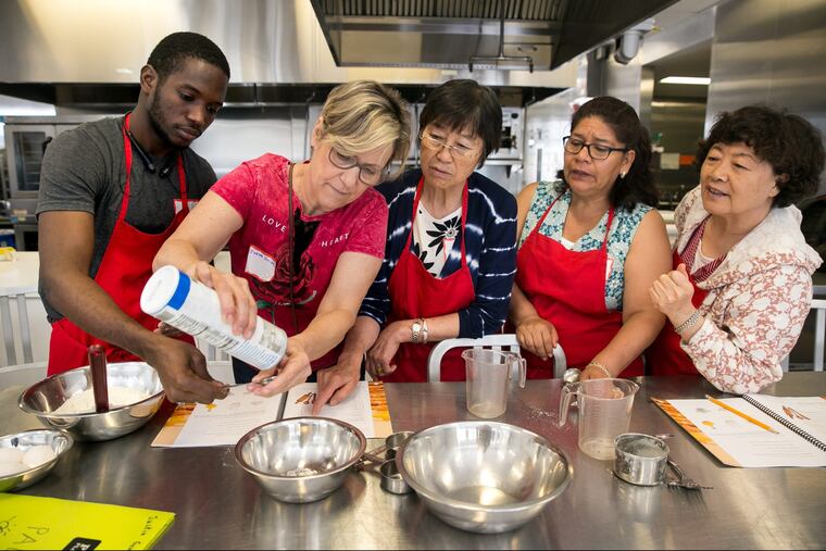 (Left to Right) Mamadou Hady Barry from Guinea, Ivana Guidelli from Brazil, Jiyun Li from China, Gloria Conchola from Mexico, and Yu Qi from China, work together during a program at the Free Library that teaches English to newcomers through cooking, at the Culinary Literacy Center at the Central Library in 2018.