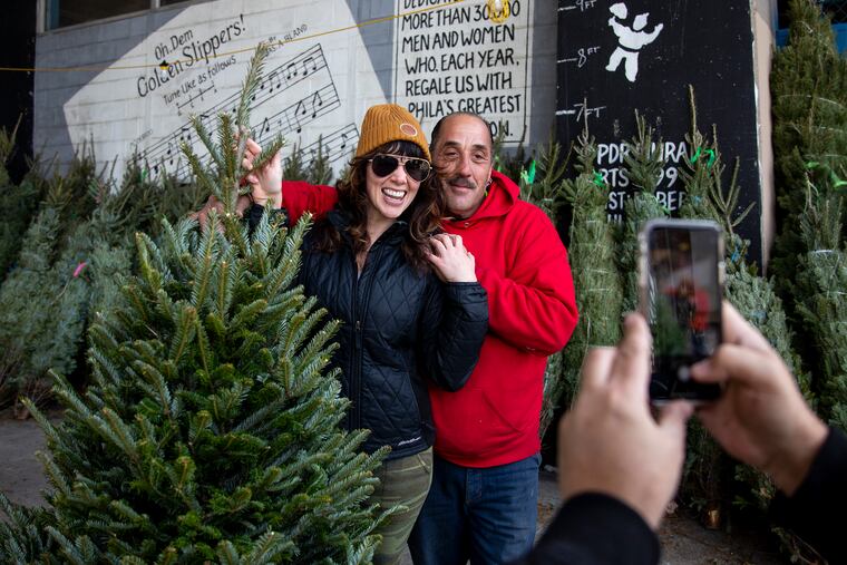 Rocky Yo-Mo, 49, of South Philadelphia, owner of Rocky Yo-Mo's Christmas Trees, takes a photo with Britni Volkman, 30, of South Philadelphia, with her tree she picked out and bought on Saturday, Nov. 30, 2019. Volkman is recovering from a broken foot and was searching for a place that delivered Christmas trees. "Out of all my tree buying experiences this is by far the best," Volkman said. "The humbleness and the Philly love."