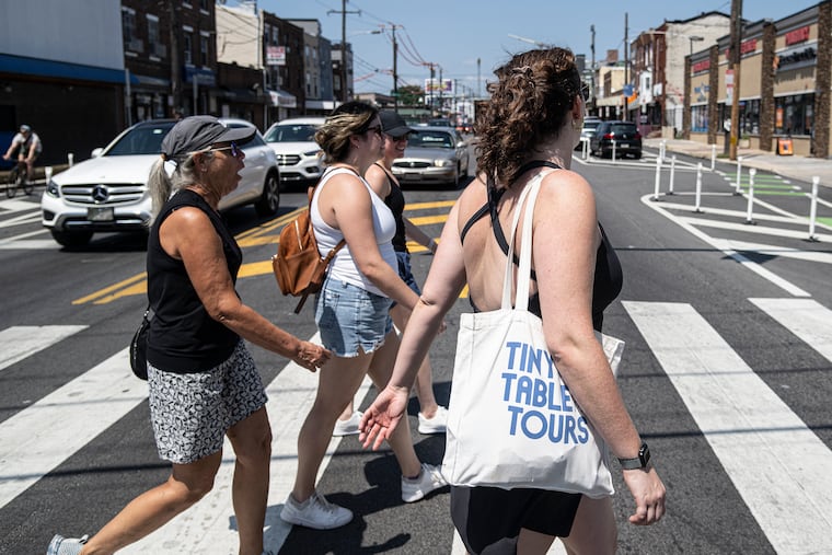 Maddy Sweitzer-Lammé (right), the founder of Tiny Table Tours, walks the streets of Philadelphia with Florida tourists Mary Pat Murphy (from left), Katie Murphy, and Maggie Murphy in South Philadelphia.