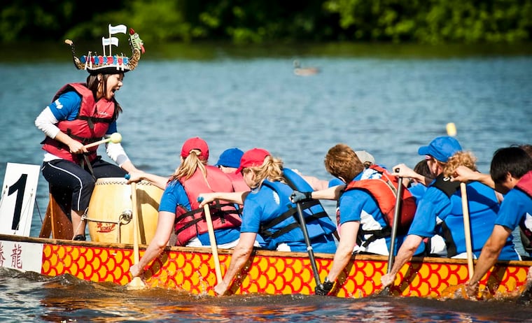 Sue Heo, sporting a hand made dragon boat hat, with the West Pharmacutical Dragon Phyre team bangs out a beat as her teams drummer during their race in the Independence Dragon Boat Regatta on the Schuylkill. (RON TARVER / Staff Photographer )