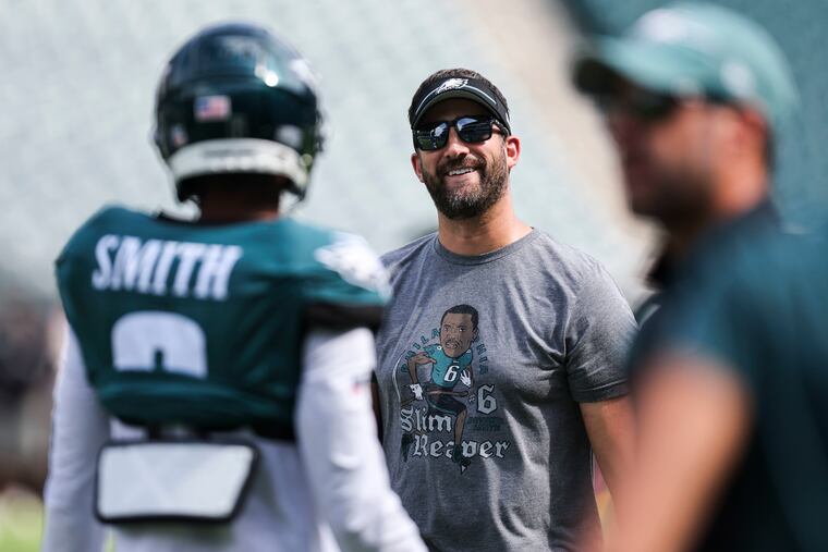 Philadelphia Eagles head coach Nick Sirianni talks with wide receiver DeVonta Smith while wearing a "Slim Reaper" t-shirt.