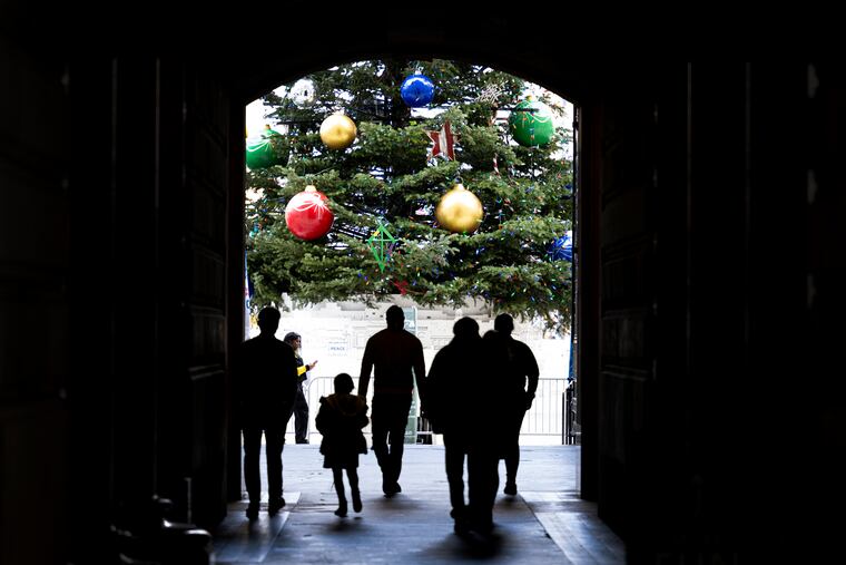 Pedestrians walked through a doorway at City Hall while approaching a 55-foot-tall Christmas tree.